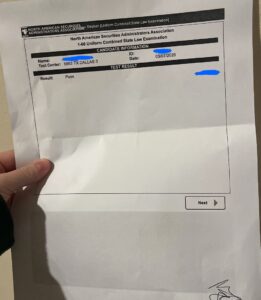 Printed Series 66 exam result sheet showing a passing result for the 1-66 exam, held in hand, with personal details covered for privacy.