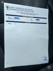 Printed Series 63 exam result sheet showing a passing result for the 1-63 exam, photographed in hand, with personal details covered for privacy.